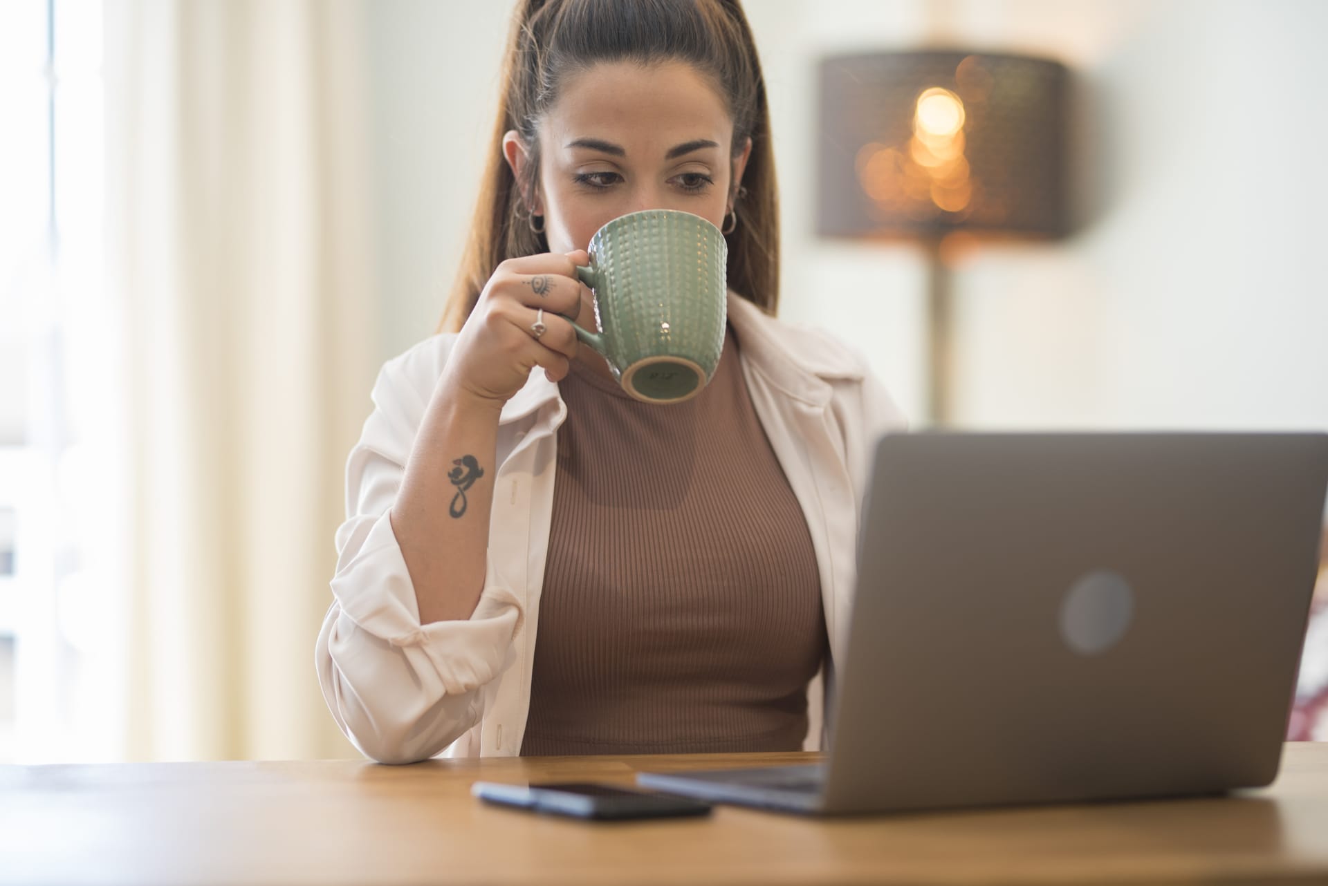 Frau mit Kaffee sitzt vor ihrem Laptop - Expertenstatus erhöhen