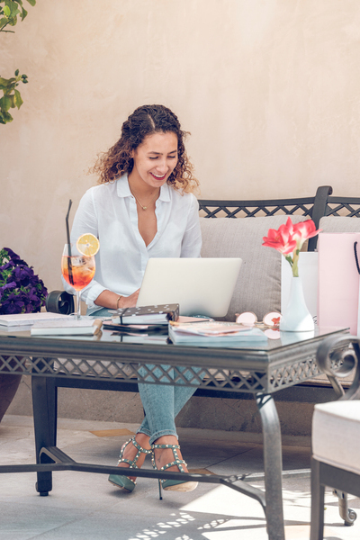 Young woman sitting in terrace and browsing laptop